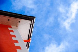 Tagrender på orange bygning med blå himmel