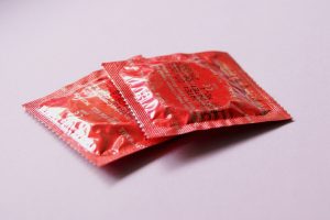 To røde kondompakker ligger på bord