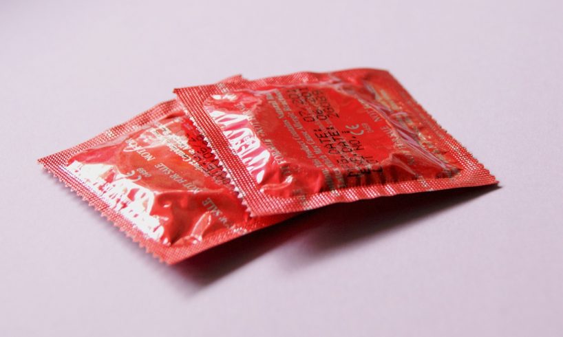 To røde kondompakker ligger på bord